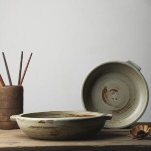 Stoneware serving plate with handles in brown glaze shown on a wooden surface
