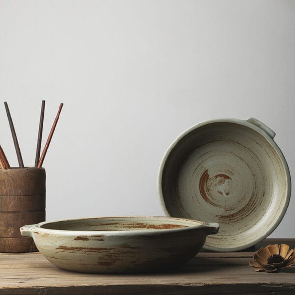Stoneware serving plate with handles in brown glaze shown on a wooden surface