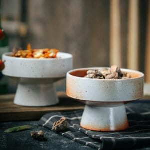Close-up of Japanese style stoneware serving bowl in Ru kiln white with high-foot design.