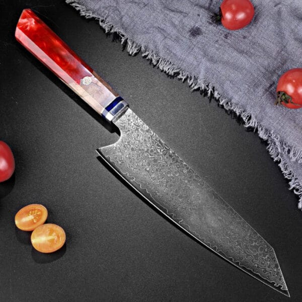 Red resin handle Damascus slicing knife laid out beside fresh ingredients